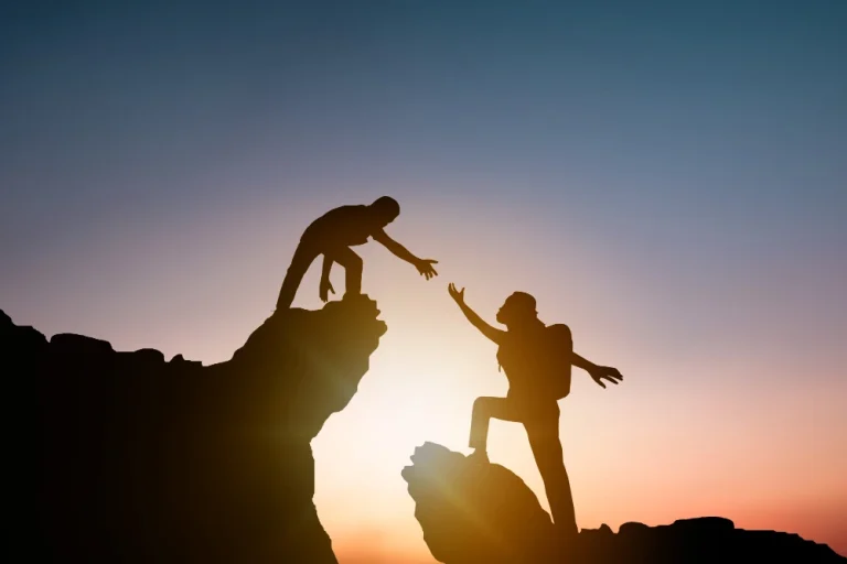 silhouette-people-helping-other-hiker-climbing-rock-mountain