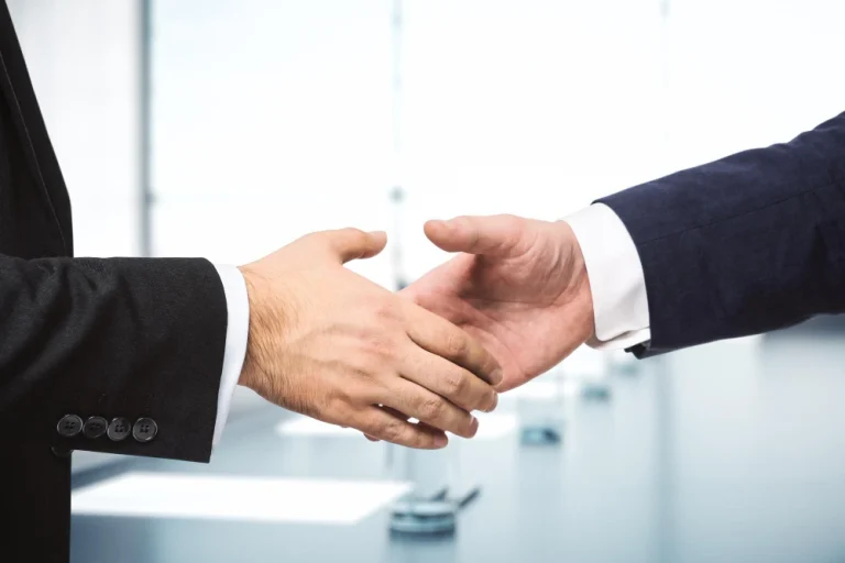 two-businessmen-shake-hands-background-sunny-meeting-room-deal-concept-close-up